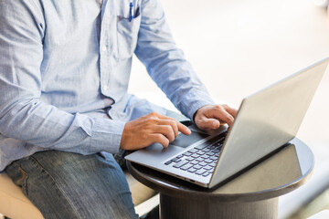 Side view of male businessman hands typing on laptop keyboard.