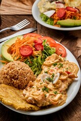 Vertical shot of a plate with Pariser schnitzel, rice, and vegetables on a wooden table