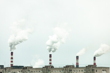 industrial chimneys with heavy smoke causing air pollution on the gray smoky sky background
