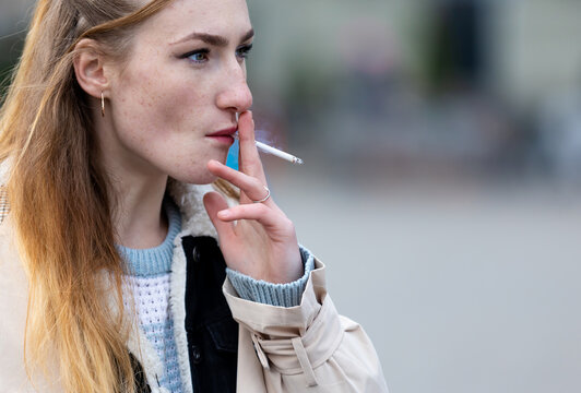 real young woman smoking outdoors, selective focus.