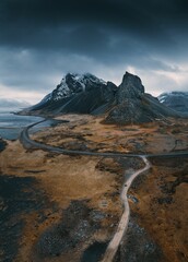 Bird's eye view of a road in a field against rocky mountains Hvalnes, Iceland on a gloomy day