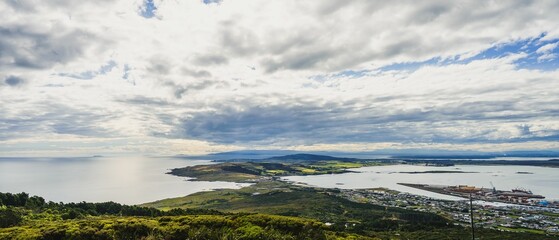 Obraz premium Panoramic view of a green forest against the sea in Invercargill, New Zealand on a cloudy day