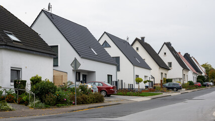 Street view of single-family houses in Germany with white facade, some of them old and two of them...