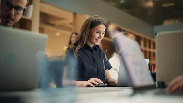 Multiethnic Creative Colleagues Working Using Laptops in a Busy Office During Day Time. Human Resources Department working on Scheduling. Female Employee Smiling. Dolly Slow Motion Shot