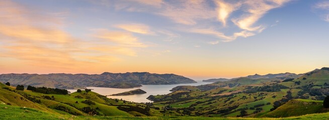 Panoramic shot of a green meadow in front of a lake, Akaroa, Banks Peninsula, New Zealand