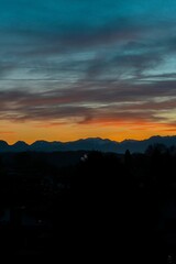 Fototapeta premium Vertical silhouette shot of alps and hills with a beautiful sunset in the background