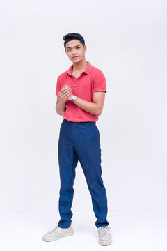 A Tall And Handsome Filipino Man In A Red Polo Shirt And Blue Jeans. Full Body Photo With White Background.