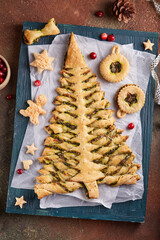 Christmas tree shape puff pastry pie with spinach, garlic and cheese, and puff pastry Linzer Christmas tree toys. Delicious homemade New Year savory baking. 