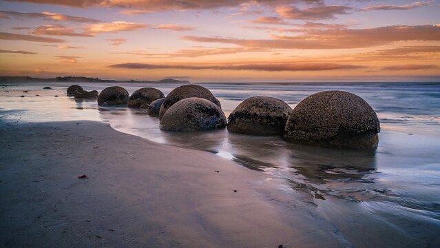 Fototapeta Round stones on the water's surface. Moeraki Boulders Beach, Hampden, New Zealand.