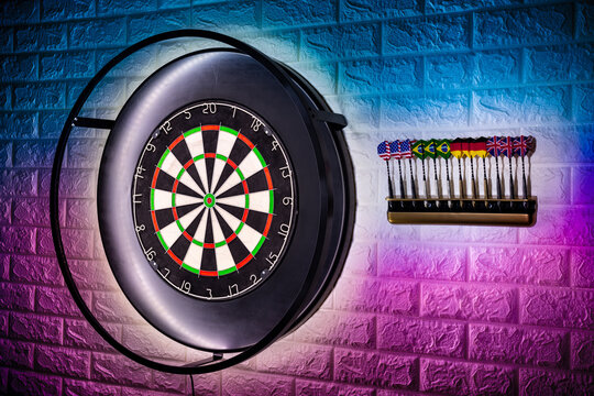professional sisal steeldart board with steel dart holder in colorful LED illumination white stone wall. leisure time hobby sport concept background.