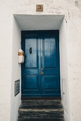 Vertical shot of blue doors on a white stone house exterior