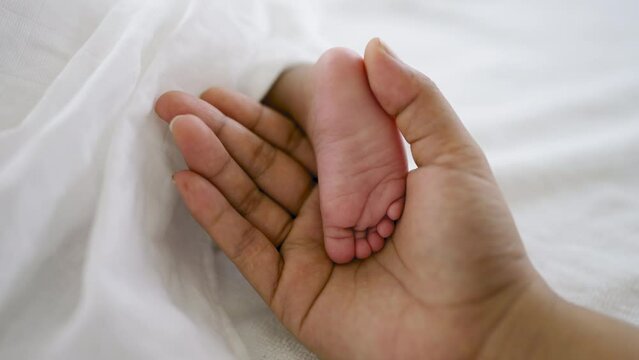 Close up father and mother hands holding newborn baby feet over black background, copy space background banner family parents love concept.