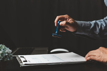 Man stamping approval of work finance banking or investment marketing documents on desk.