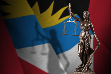 Antigua and Barbuda flag with statue of lady justice and judicial scales in dark room. Concept of...
