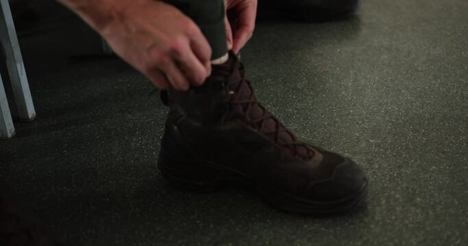 two soldiers tie their shoelaces in the barracks by the bed. hands of soldiers putting on boots. close-up