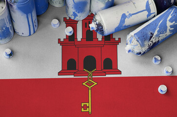 Giblartar flag and few used aerosol spray cans for graffiti painting. Street art culture concept
