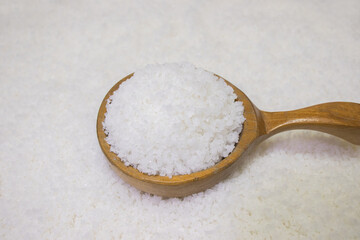 Salt in big wooden spoon on salt background.	