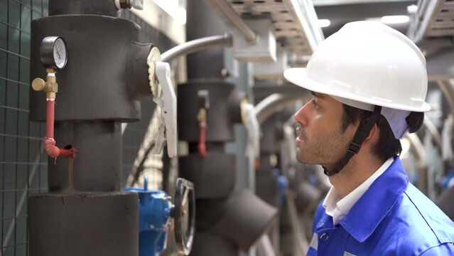 Engineers inspecting pipeline or pumping system on building rooftop.