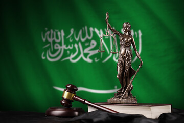 Saudi Arabia flag with statue of lady justice, constitution and judge hammer on black drapery....