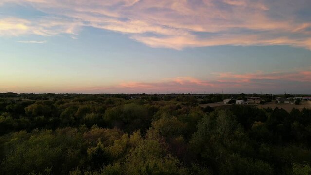 Drone flying over the wooded area at sunset with a cloudy sky in the background, Fate, Texas, US