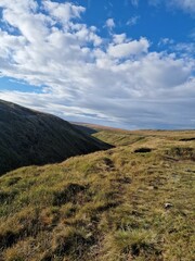Vertical of a hilly terrain under a blue cloudy sky.