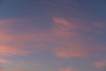 Moody sunset or sunrise sky with rays of light illuminating dark blue and bright and soft pink and orange clouds.
