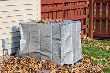 House air conditioning unit with protective cover during fall season. Concept of home air...