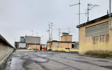 Fototapeta na wymiar Antenne tradizionali e parabole sulla copertura di un condominio di periferia