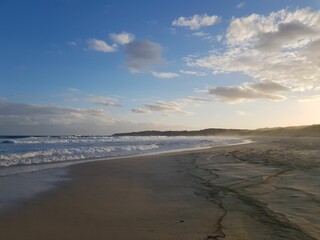 Landscape of a sandy beach under blue cloudy sky at sunrise