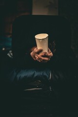 Man holding a disposable paper cup, vertical shot