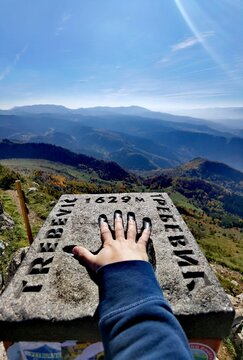 Vertical view of a hand on the landmark stone on top of mount Trebevic at the 1629-meter height