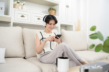 An Asian teenager wearing headphones enjoying music at home