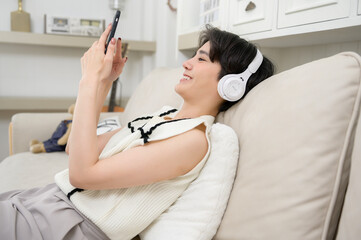 Obraz premium An Asian teenager wearing headphones enjoying music at home