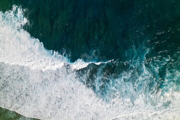 Aerial view of the ocean waves with white foam on a sunny day. Great for wallpaper
