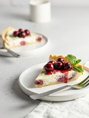 A piece of cottage cheese casserole or pudding with cherry and mint leaves on white background. Cherry cheesecake with text space