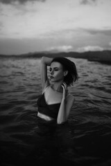 Black and white portrait of a sexy beautiful woman in the sea. Natural beauty of a young pretty girl with sexy body, clean skin and dark hair.