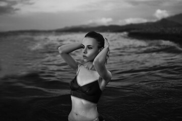 Black and white portrait of a sexy beautiful woman in the sea. Natural beauty of a young pretty girl with sexy body, clean skin and dark hair.