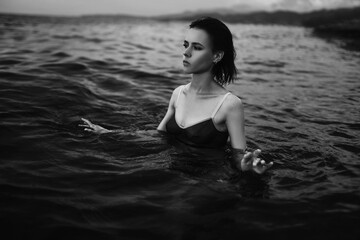 Black and white portrait of a sexy beautiful woman in the sea. Natural beauty of a young pretty girl with sexy body, clean skin and dark hair.