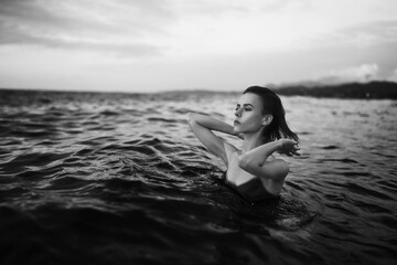 Black and white portrait of a sexy beautiful woman in the sea. Natural beauty of a young pretty girl with sexy body, clean skin and dark hair.