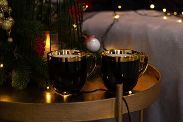 Two New Year's black cups for tea or coffee on a table in a New Year's interior