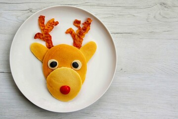 Reindeer Pancake made it from pancakes,bacon,mozzarella cheeses,black olives and tomato on plate...