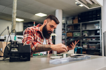 Electronics engineer working in a workshop with tin soldering parts and tablet