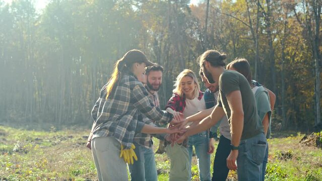 Caucasian activists, men and women with kid putting hand on hand in circle and making gesture of cooperation and coworking. Successful volunteering work together concept. Ecological activists. Outside