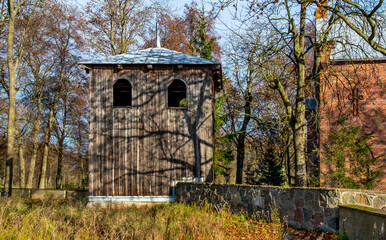 General view and architectural details of the wooden belfry and the neo-Gothic Catholic church of Saint John the Baptist built in 1874 in the village of Żmijewo Kościelne in Masovia, Poland.