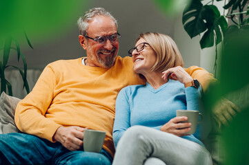 Senior couple relaxing together on the sofa at home and drinking coffee