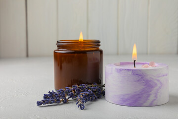 Obraz na płótnie Canvas Aromatherapy concept, candle with lavender flowers.Soy candles with lavender scent. Candles on a white texture background. Place for text. Place for copying. Spa candles with a pleasant aroma.