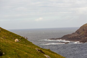 Beautiful view over a sea with foamy waves surrounded by cliffs and hills on a gloomy day