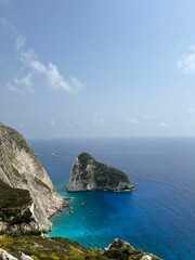 Scenic view of a small rocky mountain located next to a coastal cliff by the beach
