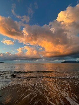 Vertical shot of a beautiful seascape with orange clouds in the background during the sunset