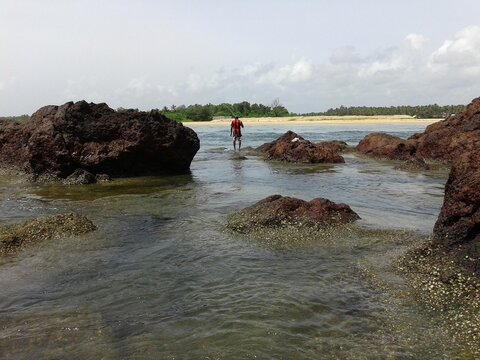 Scenic view of a man fishing on a rocky shore of a beach